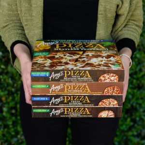 Person holding a stack of Amy's frozen pizza packages